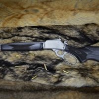 A lever-action rifle with a black stock and several bullets, displayed on a fur background.
