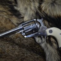 A silver revolver with an ivory handle resting on a fur surface.